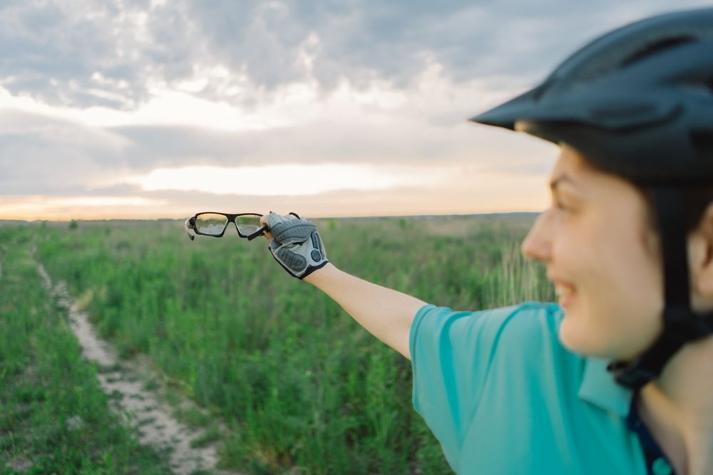 woman wearing cycling helmet holds cycling glasses